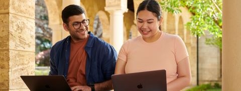 Migrant man and migrant woman studying outside on their laptops, University of Western Australia.