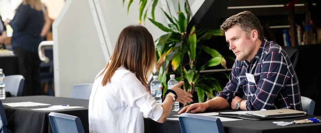 A man and woman sitting at a table, having a discussion.