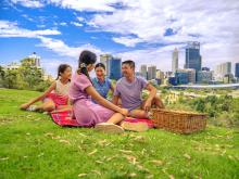 family having a picnic in front of the Perth skyline.